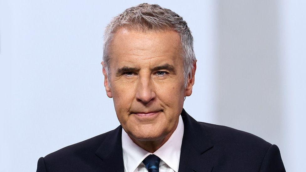 Let me think through this translation carefully:

1. “TV presenter” → “TV sunucusu” (standard Turkish term)

2. “Dermot Murnaghan” → This is a proper name, so it stays the same in Turkish

3. “dies” → “vefat etti” (more formal/respectful for news) or “hayatını kaybetti” (lost his life – very common in Turkish news)

4. “aged 68” → “68 yaşında” (standard Turkish format)

5. In Turkish